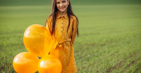 Little Girl With Yellow Balloons In The Field